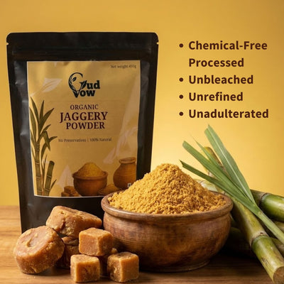 Gudvow Organic Jaggery Powder pouch with sugarcane, jaggery blocks and wooden bowl showing pure unrefined jaggery.
